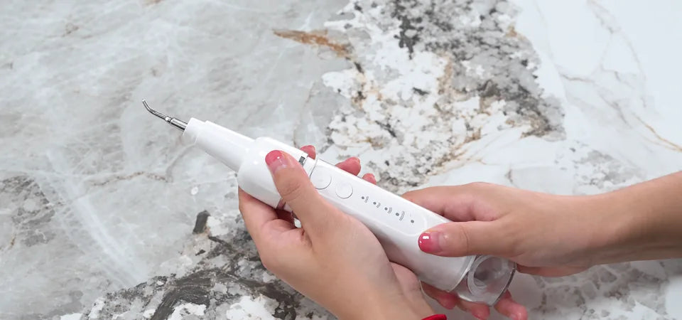 ToothForm Scaler held in two hands, showing the tip, controls and water reservoir